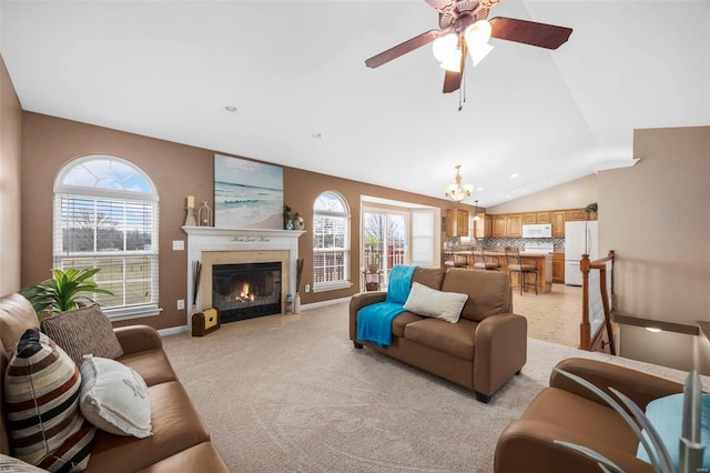 living area featuring a healthy amount of sunlight, a fireplace with flush hearth, vaulted ceiling, and light colored carpet