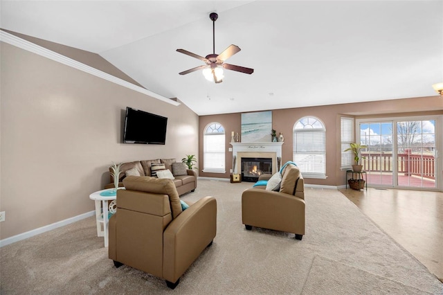 carpeted living room featuring ceiling fan, baseboards, vaulted ceiling, and a glass covered fireplace