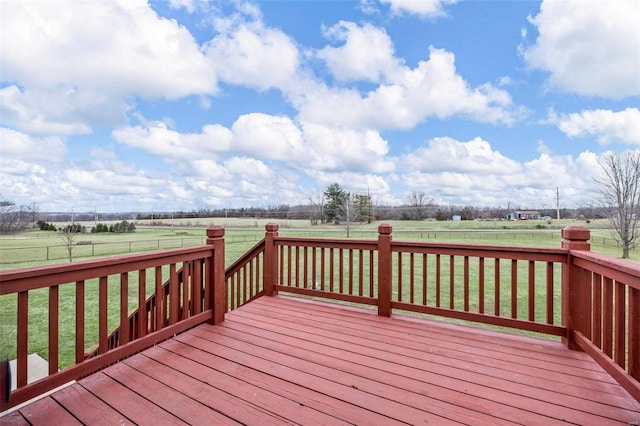 deck featuring a rural view, fence, and a lawn