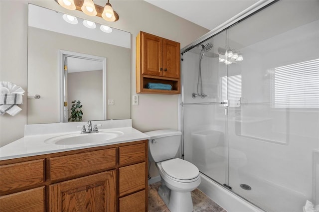 bathroom featuring toilet, a shower stall, and vanity