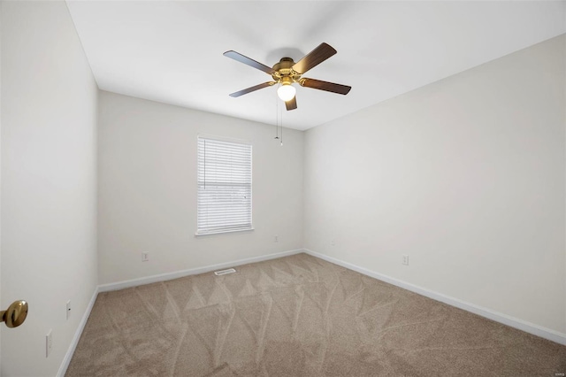 spare room with baseboards, ceiling fan, and light colored carpet