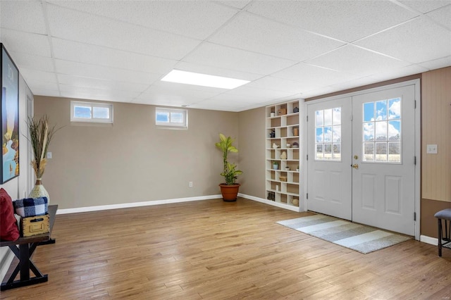 foyer with french doors, a drop ceiling, baseboards, and wood finished floors