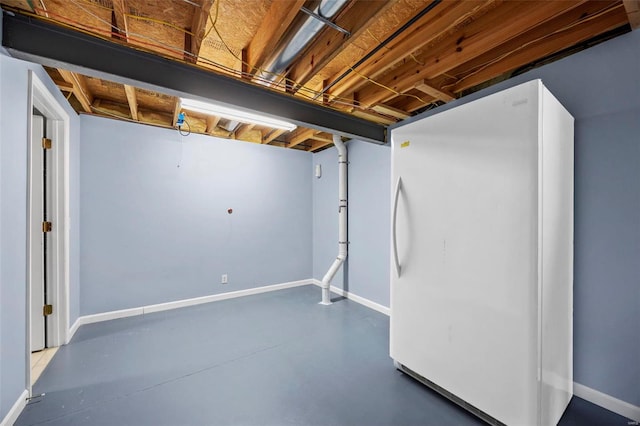 unfinished below grade area featuring freestanding refrigerator and baseboards