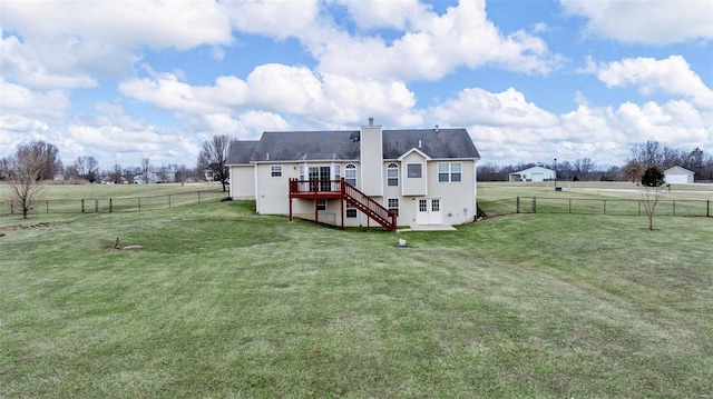 back of house with a fenced backyard, a chimney, a rural view, stairs, and a yard