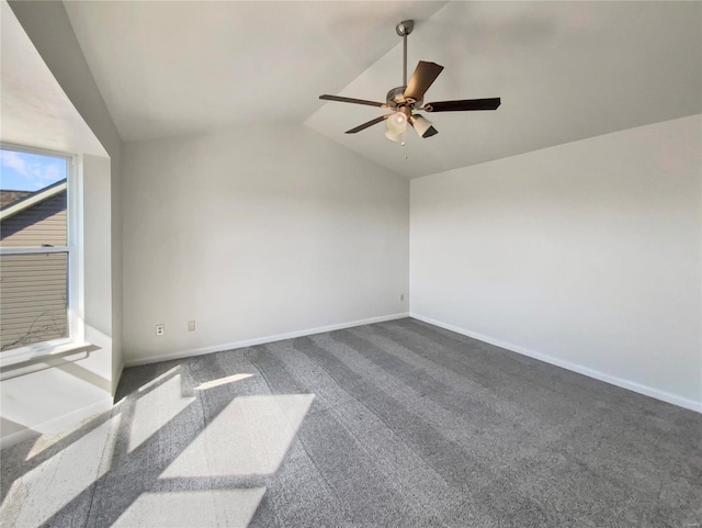 spare room featuring dark carpet, vaulted ceiling, baseboards, and ceiling fan