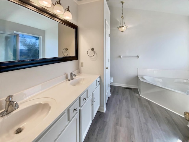 full bath featuring toilet, a bath, a sink, and wood finished floors