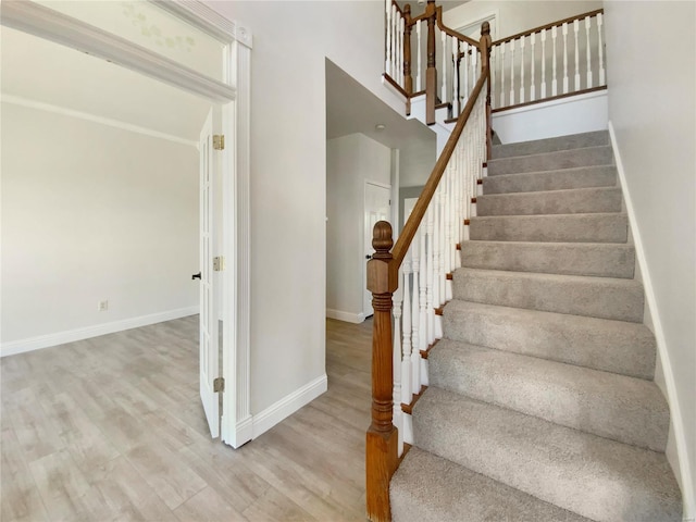 staircase featuring wood finished floors and baseboards