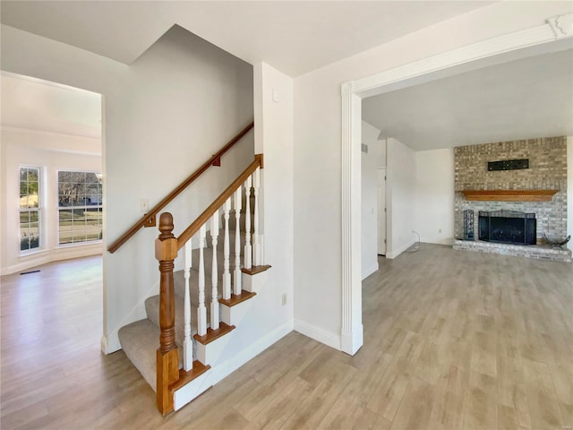 staircase featuring a fireplace, wood finished floors, and baseboards