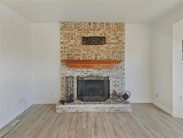 unfurnished living room with a fireplace, baseboards, and wood finished floors