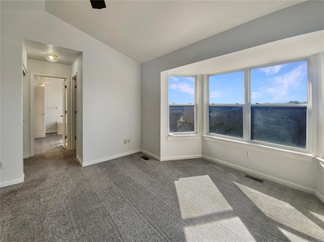 unfurnished room featuring dark carpet, visible vents, vaulted ceiling, and baseboards