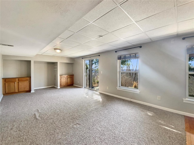 carpeted spare room with visible vents, a paneled ceiling, and baseboards