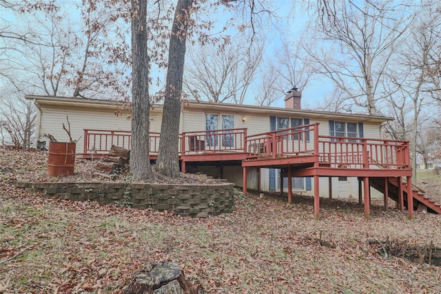 back of property featuring stairway, a wooden deck, and a chimney