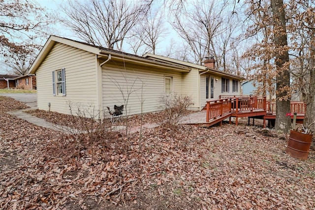 view of side of property featuring a chimney and a wooden deck