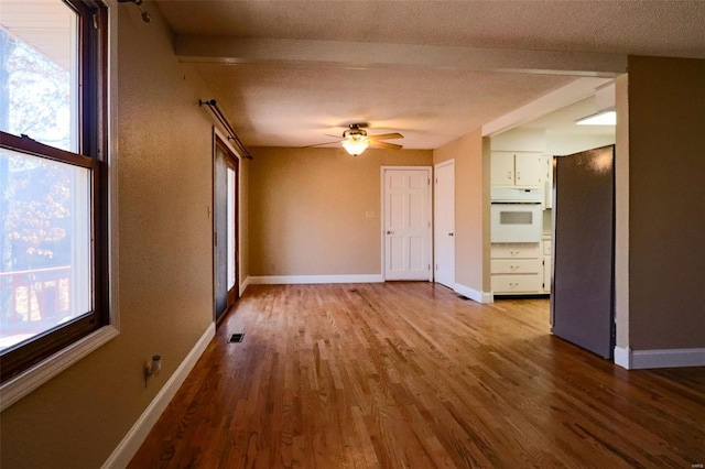 unfurnished living room with plenty of natural light, baseboards, and wood finished floors