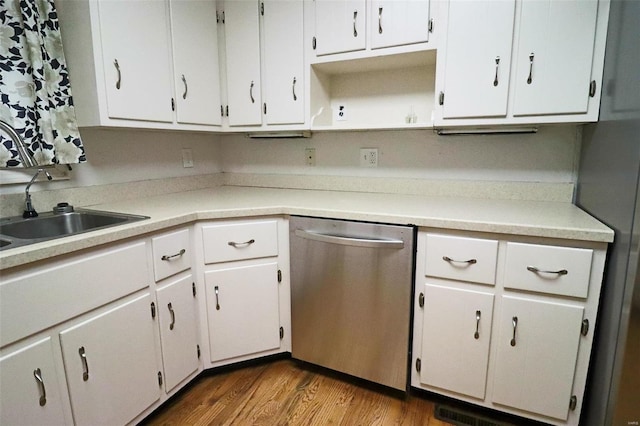 kitchen featuring light countertops, stainless steel dishwasher, dark wood-style floors, white cabinetry, and a sink