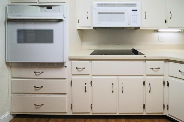 kitchen featuring white appliances, white cabinets, and light countertops