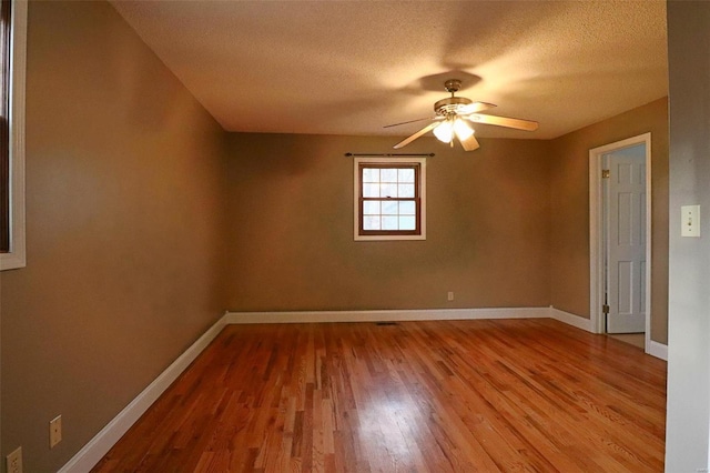 unfurnished room featuring a ceiling fan, wood finished floors, baseboards, and a textured ceiling