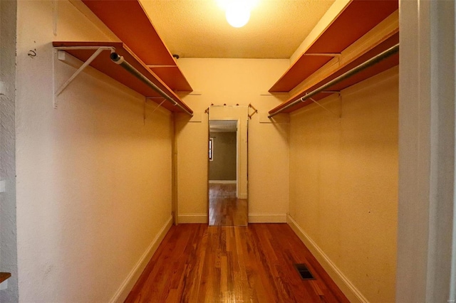 spacious closet featuring dark wood finished floors and visible vents