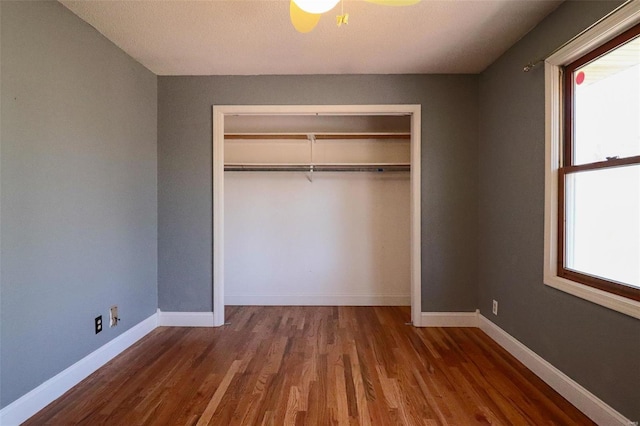 unfurnished bedroom with a closet, baseboards, and wood finished floors