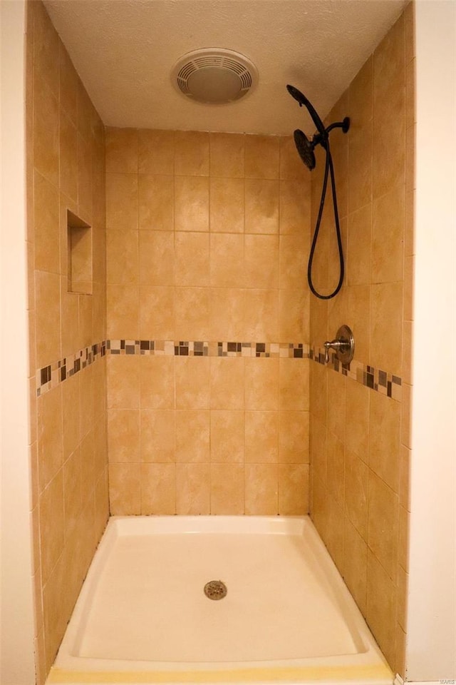 bathroom featuring a textured ceiling and a tile shower