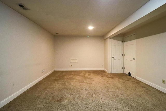 finished below grade area featuring visible vents, carpet floors, and baseboards