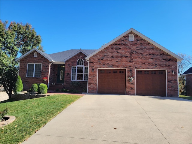 ranch-style home featuring driveway, a front lawn, an attached garage, and brick siding