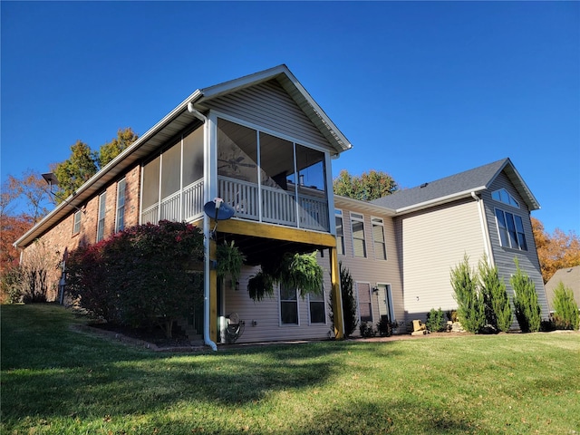 rear view of property featuring a sunroom and a lawn