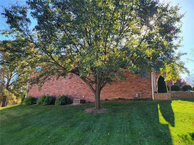 view of property exterior with central air condition unit, a lawn, and brick siding