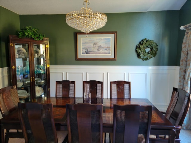 dining space with a decorative wall, wainscoting, and an inviting chandelier