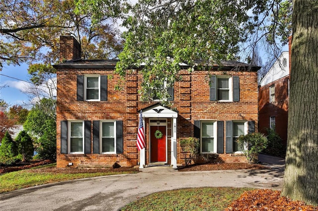 colonial-style house featuring brick siding and a chimney