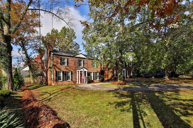 view of front of property with a front yard, brick siding, fence, and a chimney