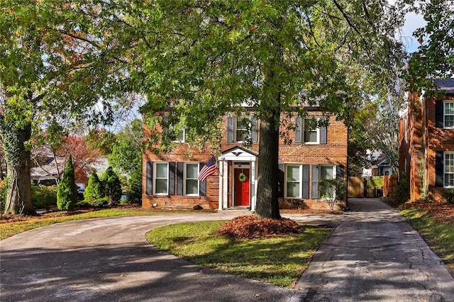 view of front of house with brick siding, fence, and driveway