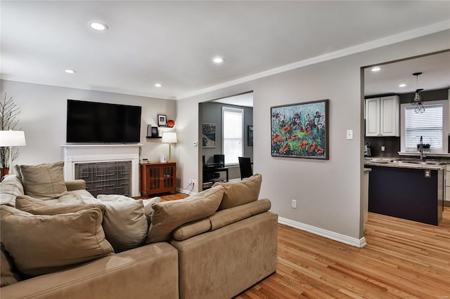 living room with ornamental molding, light wood-type flooring, recessed lighting, and baseboards