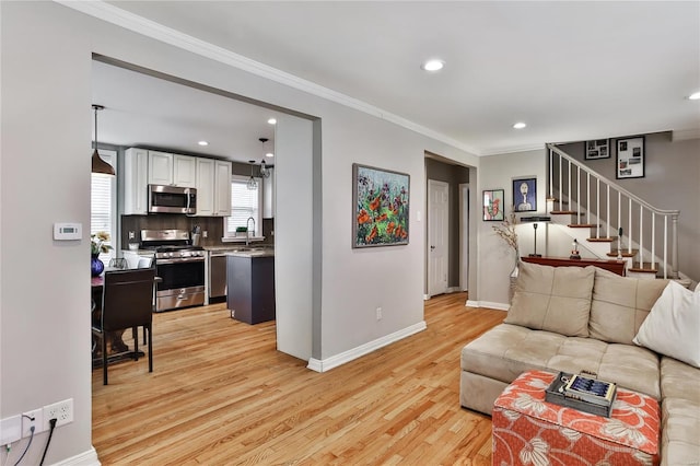 living area with light wood finished floors, baseboards, stairway, ornamental molding, and recessed lighting