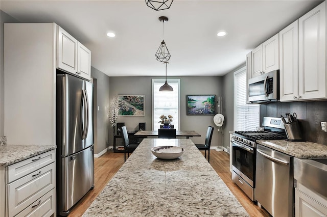 kitchen featuring baseboards, stainless steel appliances, white cabinetry, and light wood-style floors