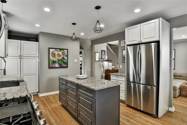 kitchen featuring light wood-style floors, white cabinetry, light stone counters, and freestanding refrigerator