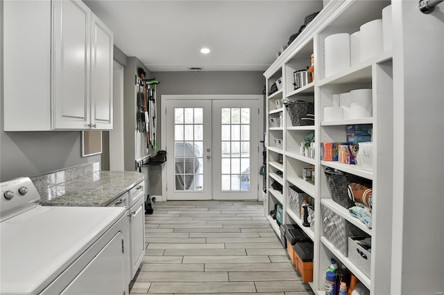 washroom featuring wood finish floors, french doors, cabinet space, and washing machine and clothes dryer