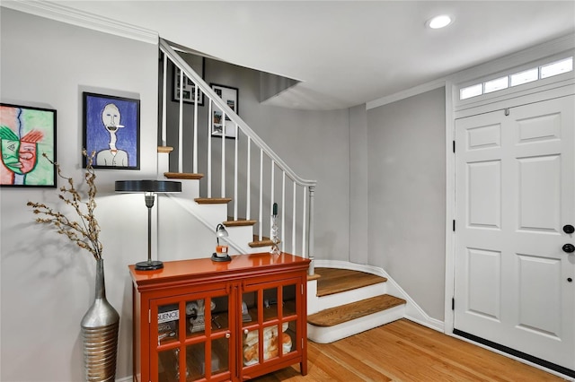 entryway with baseboards, crown molding, stairway, and wood finished floors