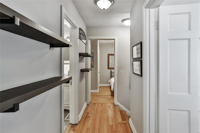 hallway with light wood-type flooring and baseboards