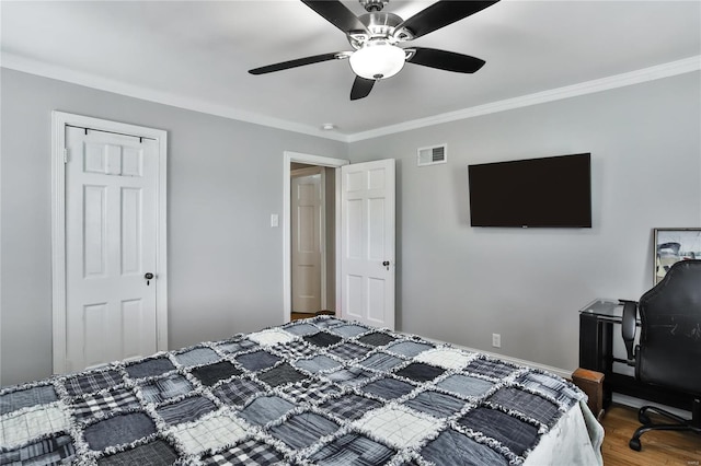 bedroom with baseboards, visible vents, ceiling fan, wood finished floors, and crown molding