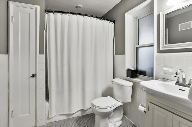 full bathroom featuring visible vents, toilet, vanity, and tile walls