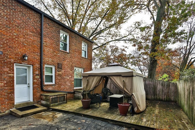 rear view of property with entry steps, brick siding, fence, and a gazebo