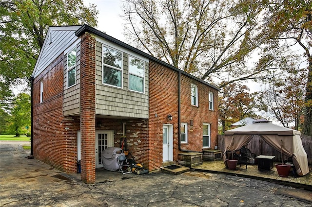 rear view of house featuring a patio area, a gazebo, and brick siding