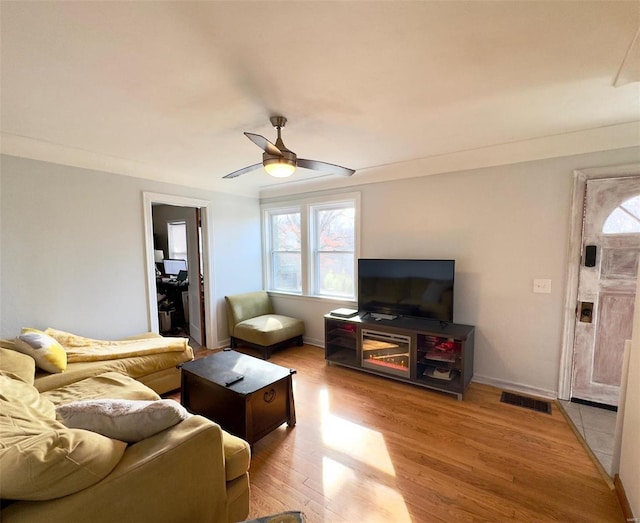 living area featuring ceiling fan, wood finished floors, visible vents, and baseboards