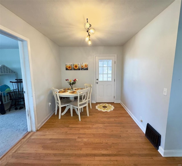 dining area with light wood-style flooring, visible vents, and baseboards