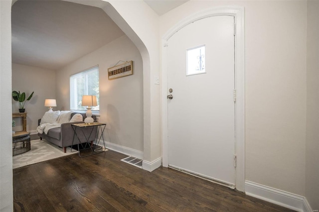 entryway with a wealth of natural light, baseboards, arched walkways, and wood finished floors