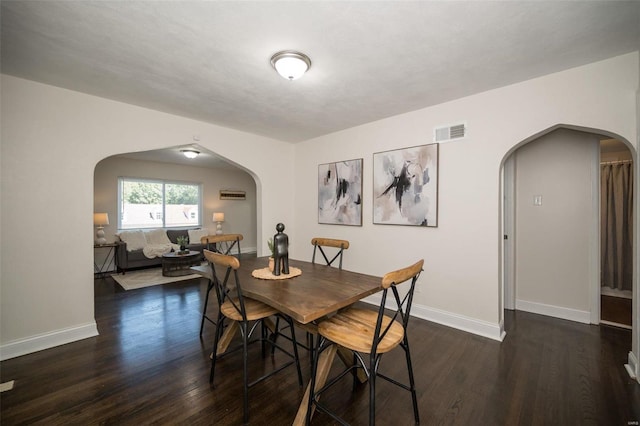 dining space featuring visible vents, arched walkways, and wood finished floors