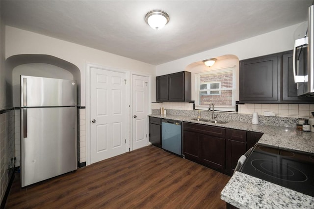 kitchen with stainless steel appliances, light stone counters, dark wood-style flooring, and a sink