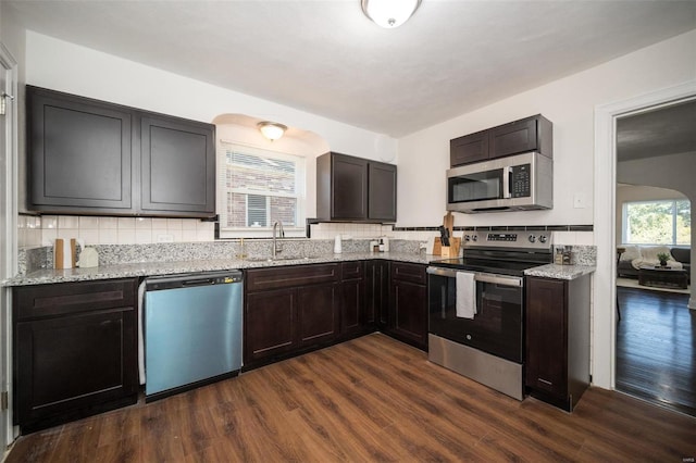 kitchen featuring backsplash, dark wood finished floors, stainless steel appliances, and a sink