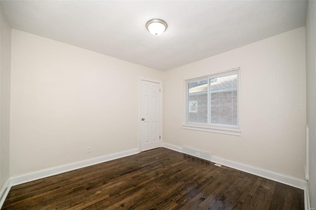 spare room featuring baseboards, visible vents, and dark wood-style flooring